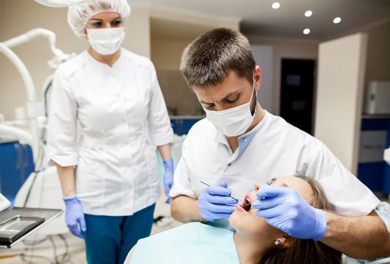 A dentist is examining a woman 's teeth in a dental office.