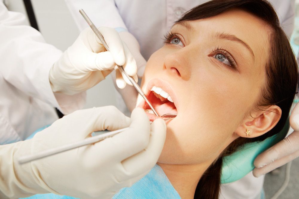 A woman is getting her teeth examined by a dentist.