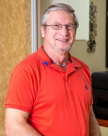 A man wearing a red polo shirt and glasses is smiling for the camera.