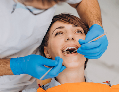 A woman is having her teeth examined by a dentist.