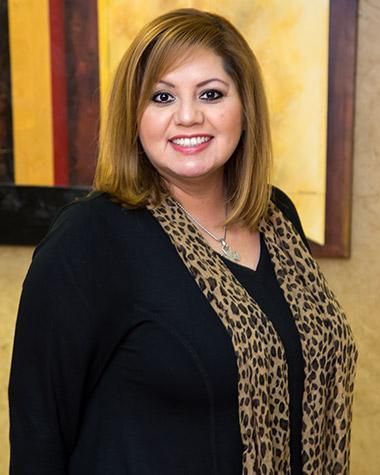 A woman wearing a black sweater and a leopard print scarf is smiling for the camera.