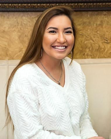 The woman is wearing a white sweater and smiling for the camera.