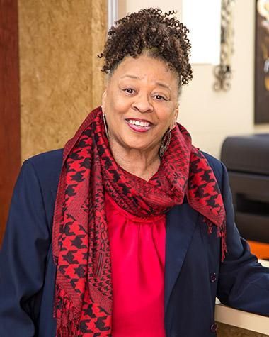 A woman wearing a red shirt and a scarf is smiling for the camera.