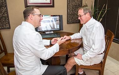 Two men are sitting at a table talking to each other.