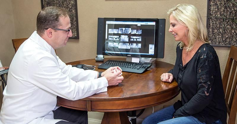 A woman is sitting at a table talking to a doctor.