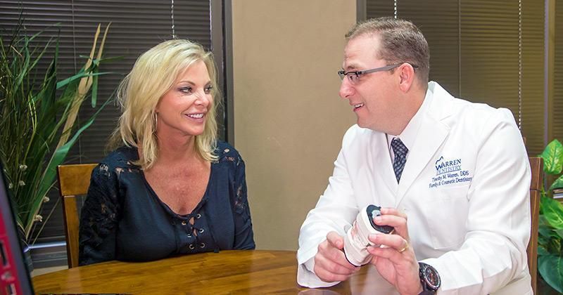 A woman is sitting at a table talking to a doctor.