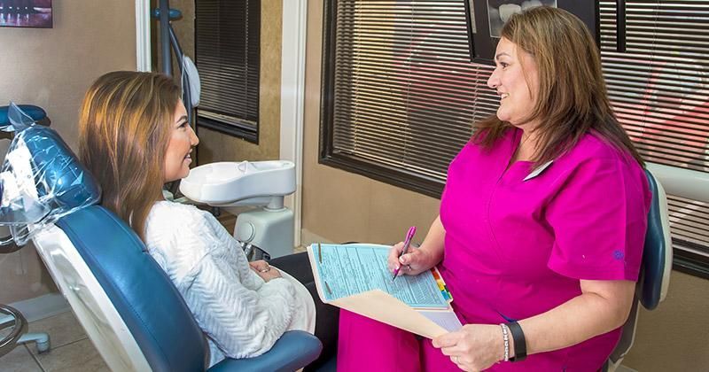 A dentist is talking to a patient in a dental chair.