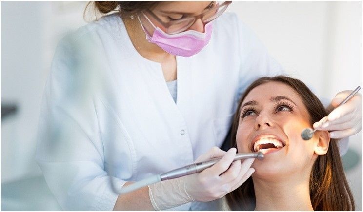 A woman is getting her teeth examined by a dentist.