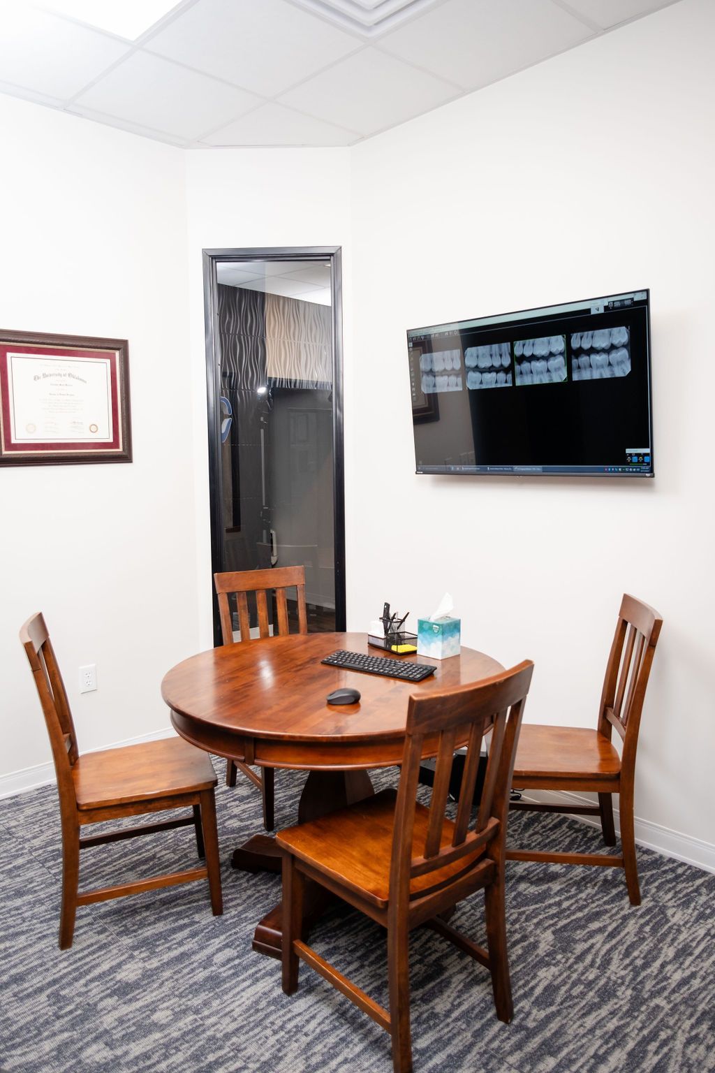 A dining room with a table and chairs and a painting on the wall.