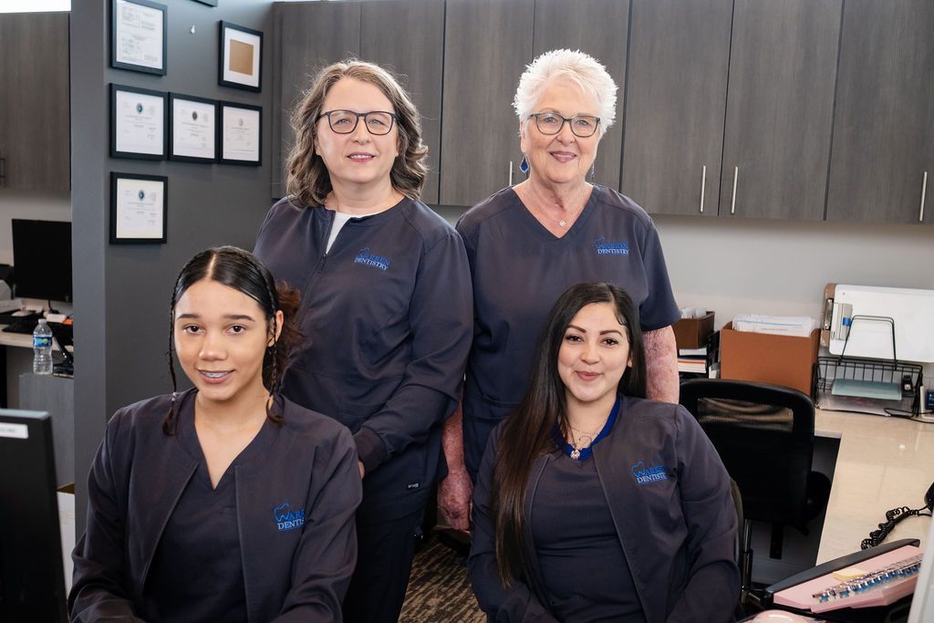 Two women are shaking hands at a dental office counter.