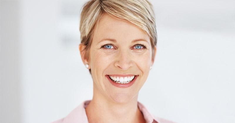 A woman with short blonde hair is smiling for the camera.