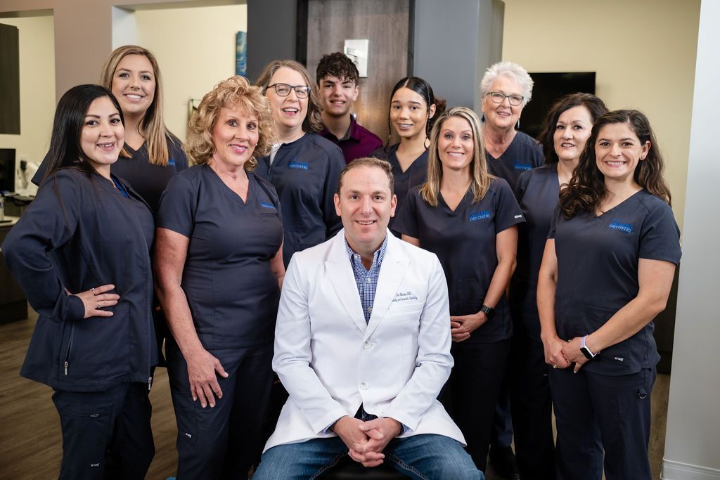 A group of women in pink scrubs are posing for a picture while sitting on a couch.