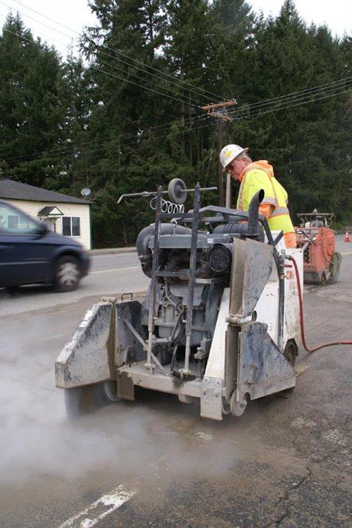 Worker sawing concrete street - Complete concrete cutting services in Milton, WA