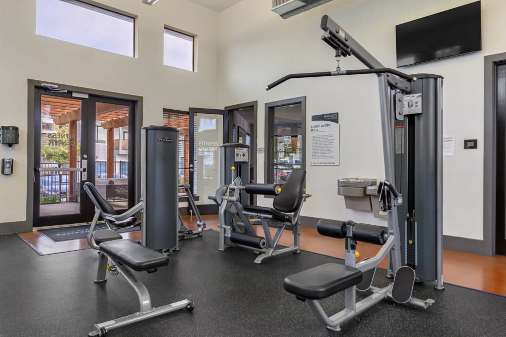 A gym with a lot of equipment and a television on the wall at Marquis SoCo in South Austin, TX.