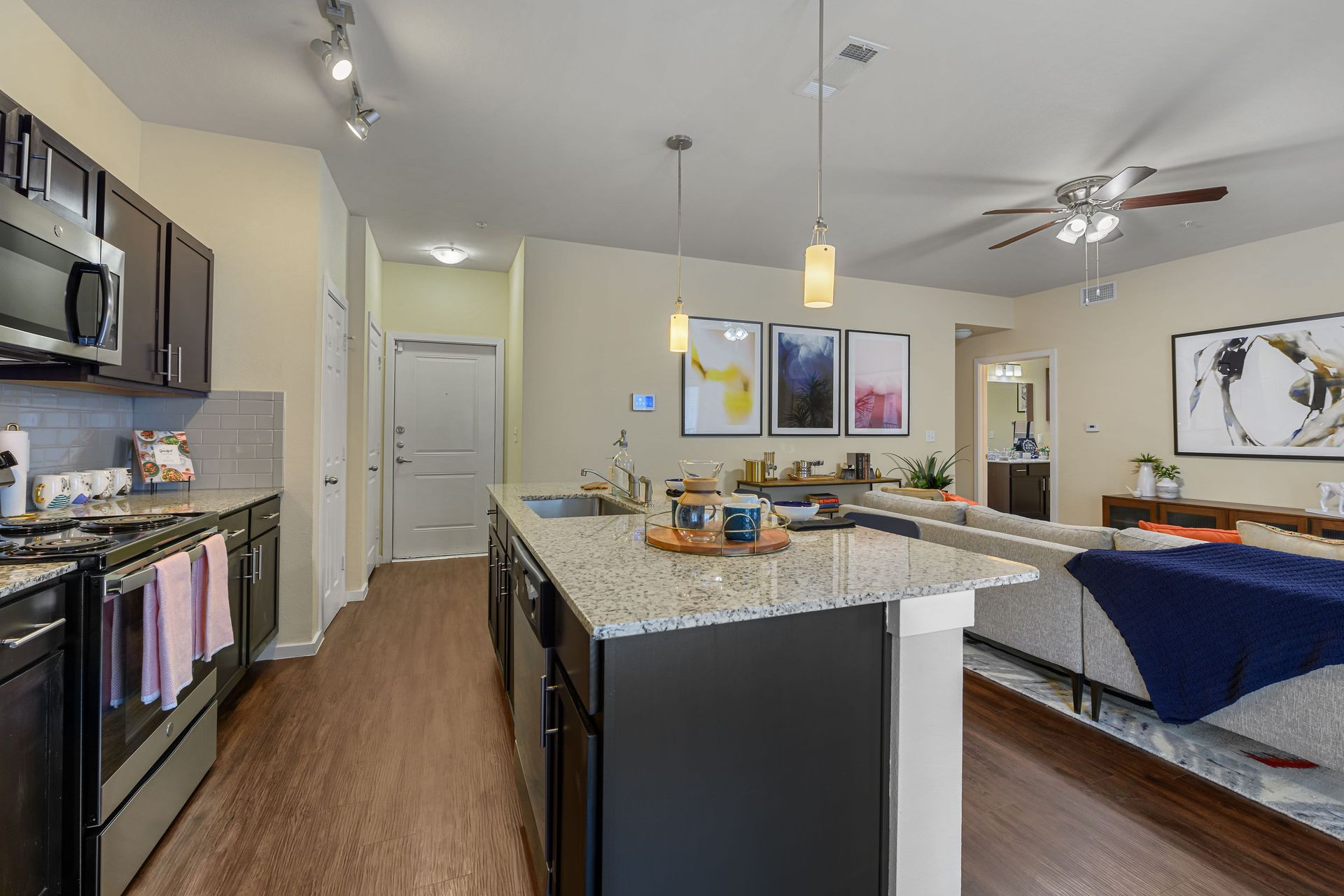 Apartment kitchen with granite countertops, stainless steel appliances, and a ceiling fan at Marquis SoCo in South Austin, TX.