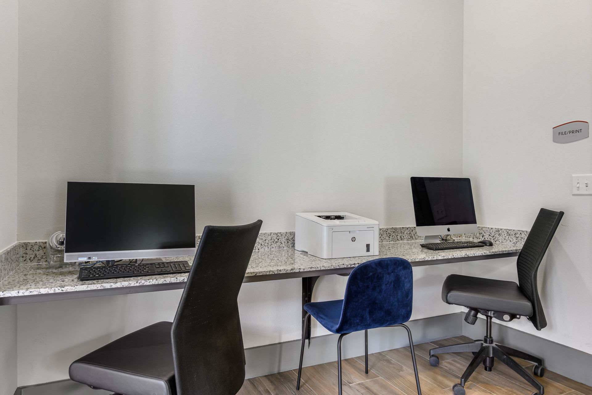 Business center with a desk, chairs, computers and a printer at Marquis SoCo in South Austin, TX.