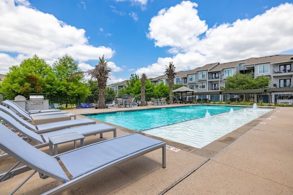 A swimming pool surrounded by lounge chairs at Marquis SoCo in South Austin, TX.