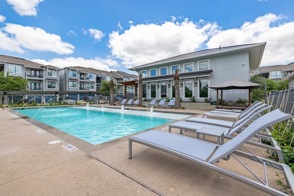 Apartment ourdoor swimming pool is surrounded by lounge chairs at Marquis SoCo in South Austin, TX.