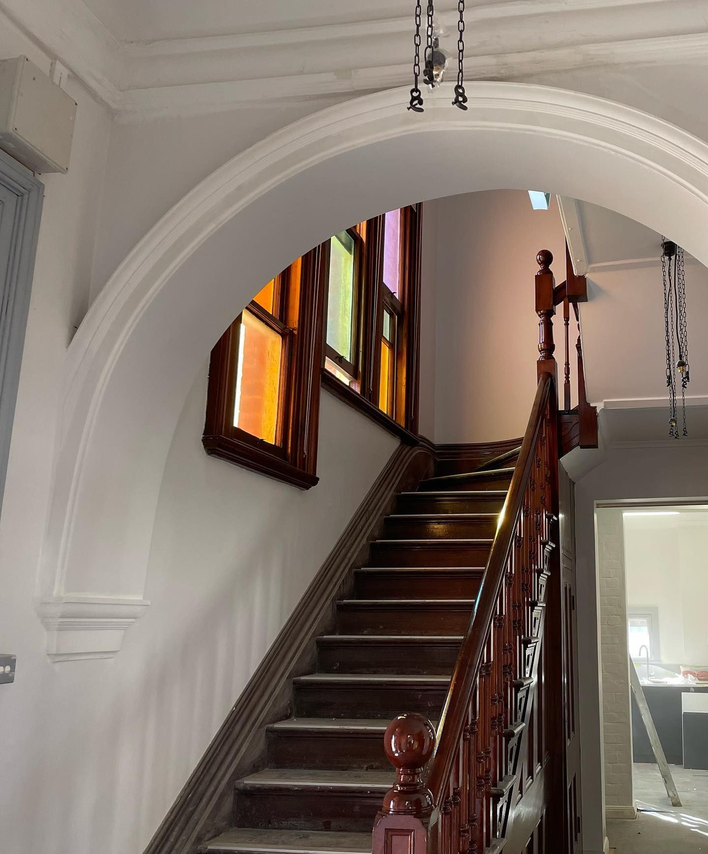 A staircase with a wooden railing and stained glass windows