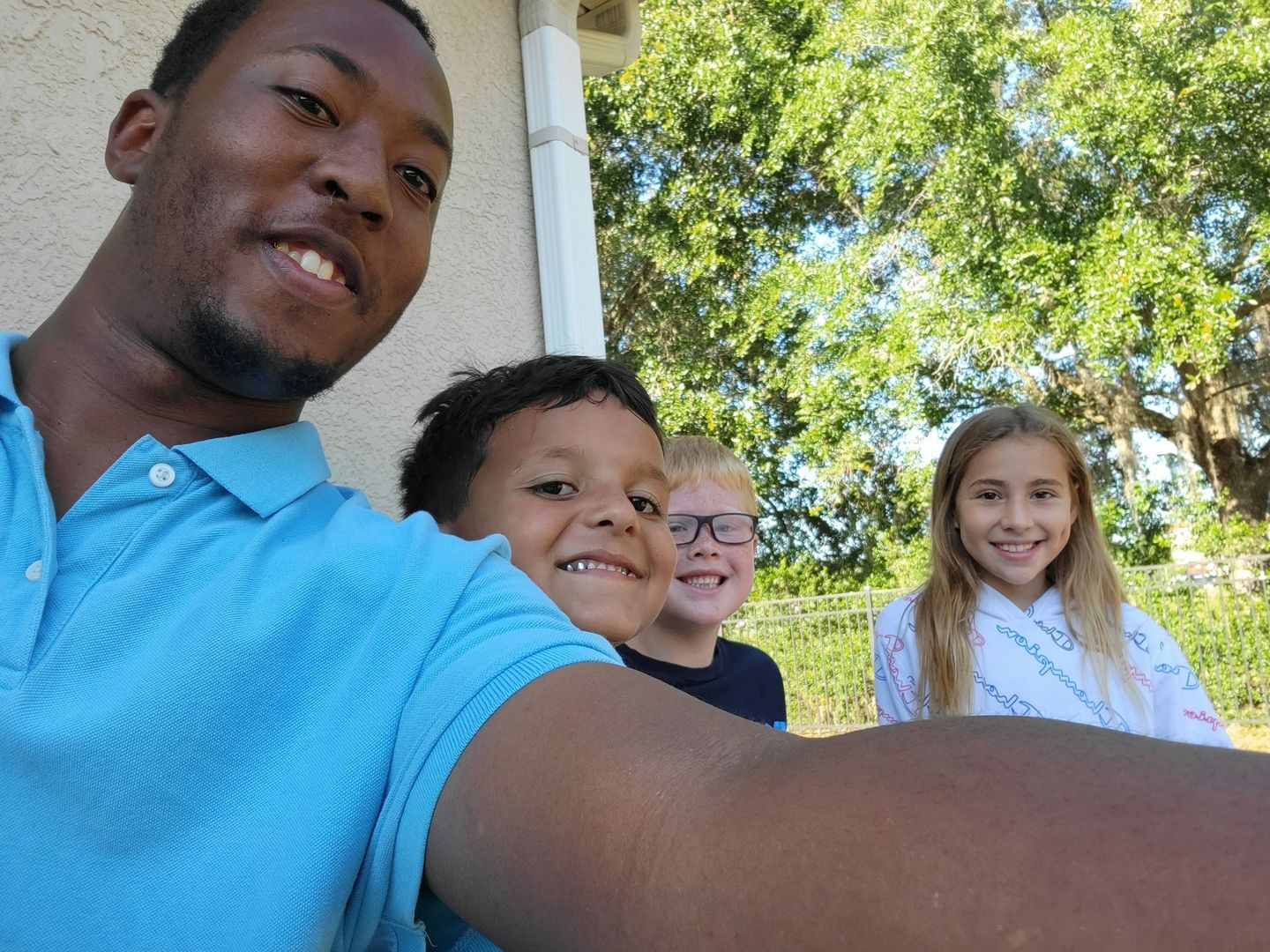 A man is taking a selfie with three children.