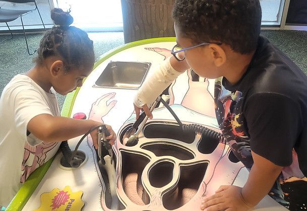 A boy and a girl are playing with a toy on a table.