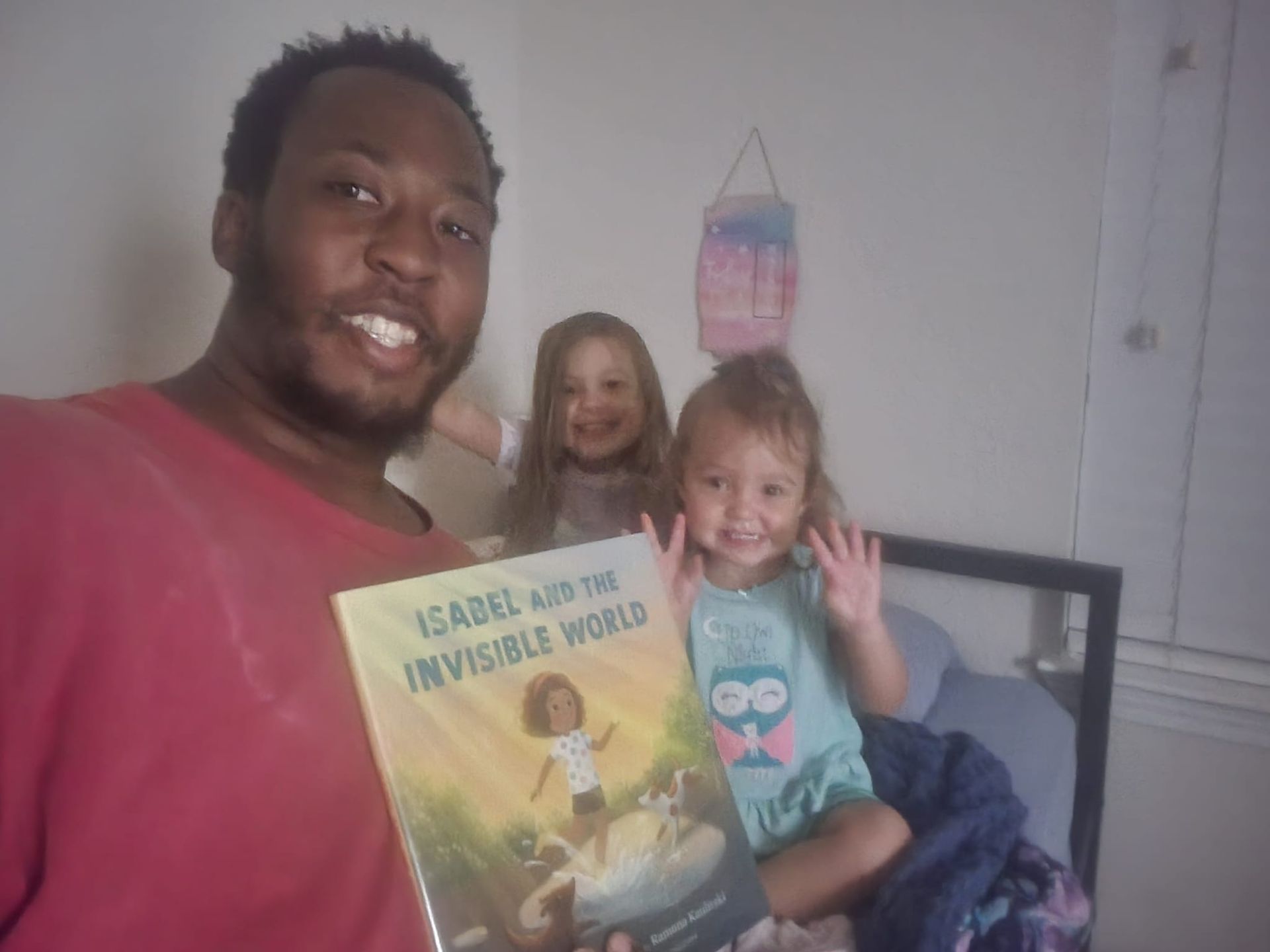 A man is holding a book in front of two little girls.