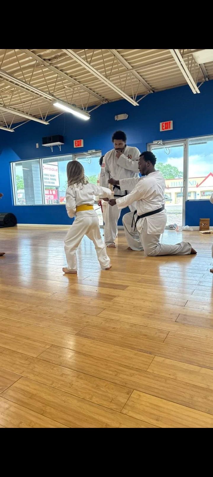 A group of people are practicing karate in a gym.