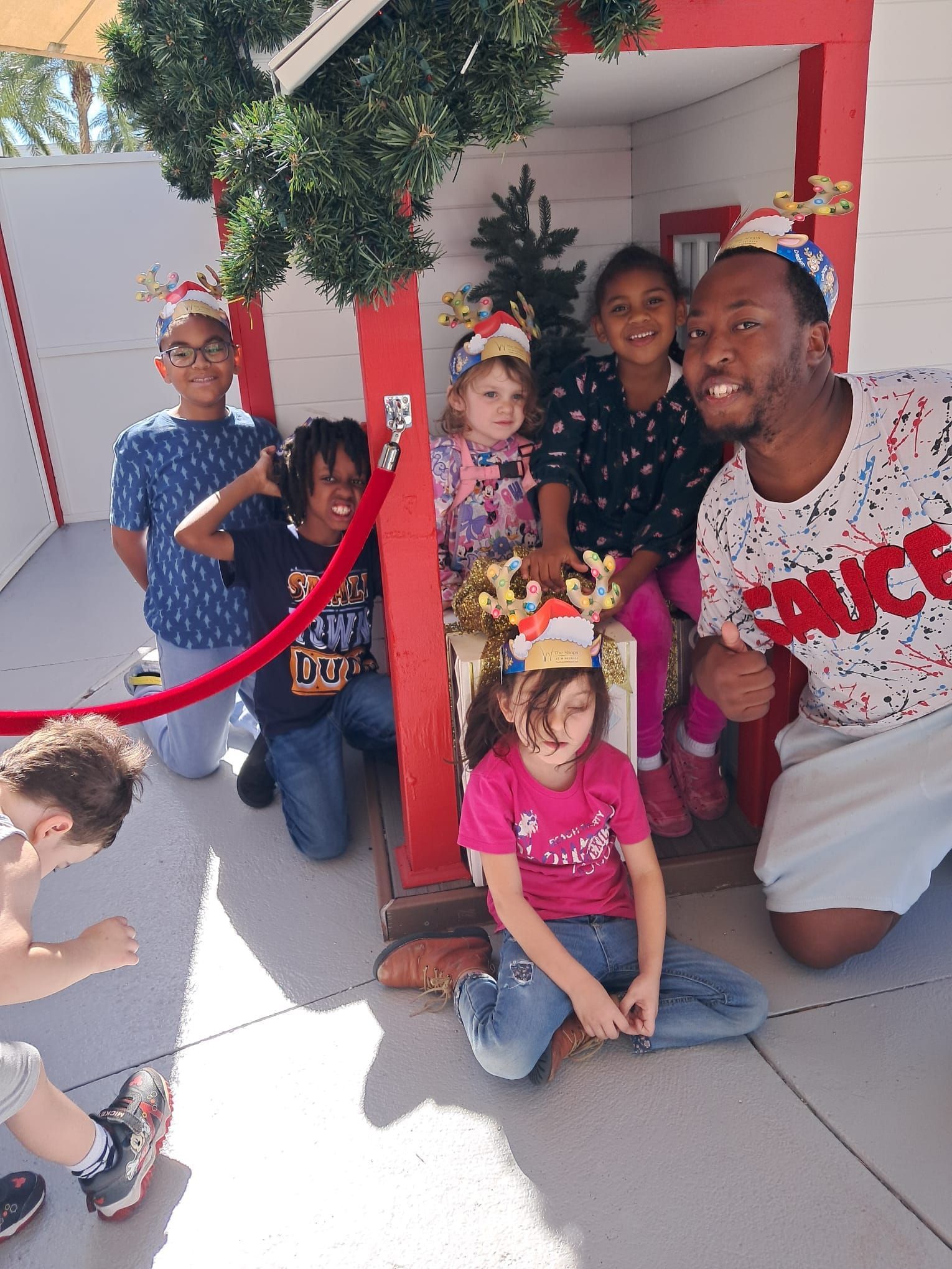 A group of children are posing for a picture in front of a playhouse.