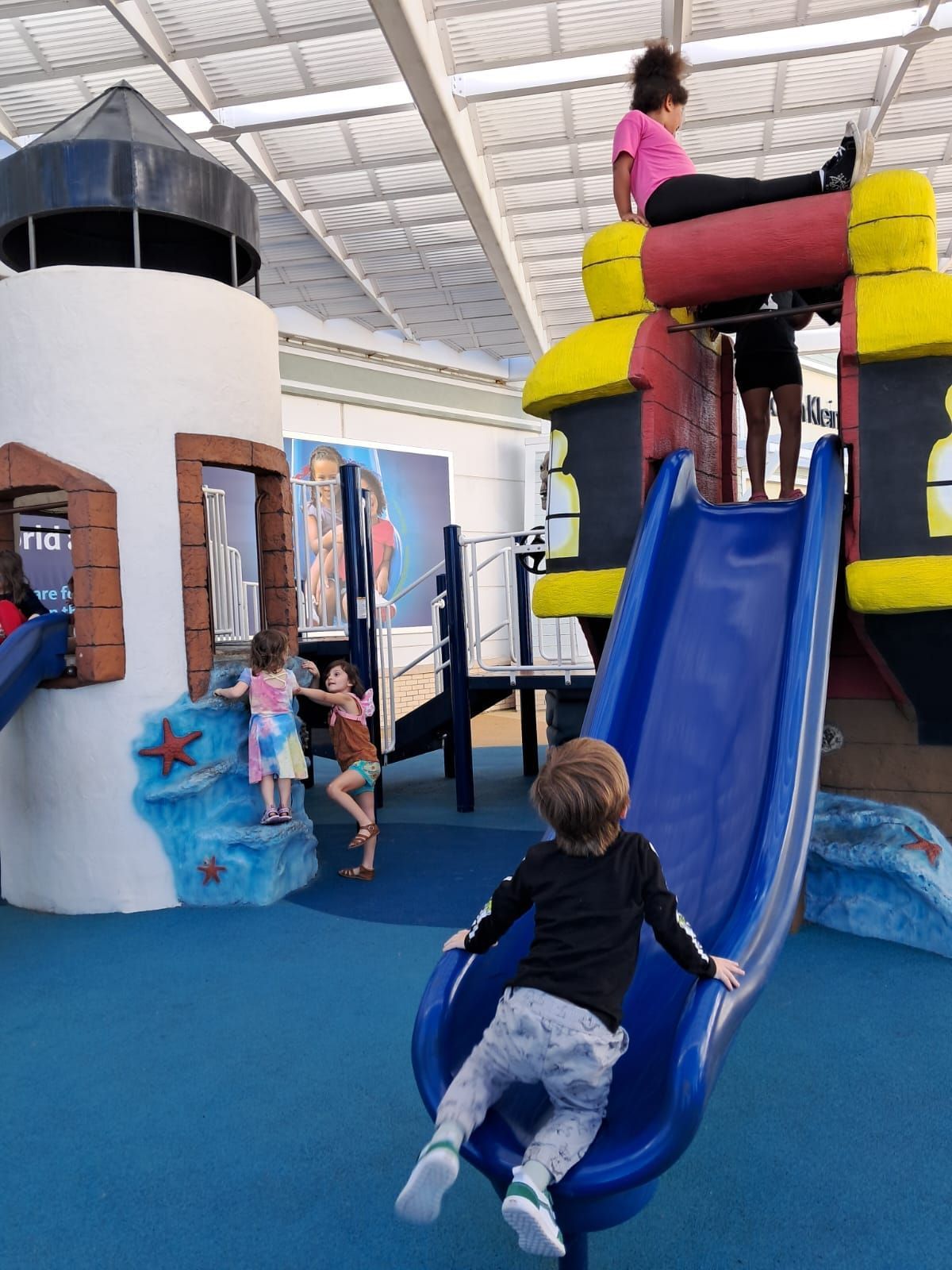 A little boy is going down a slide in a playground