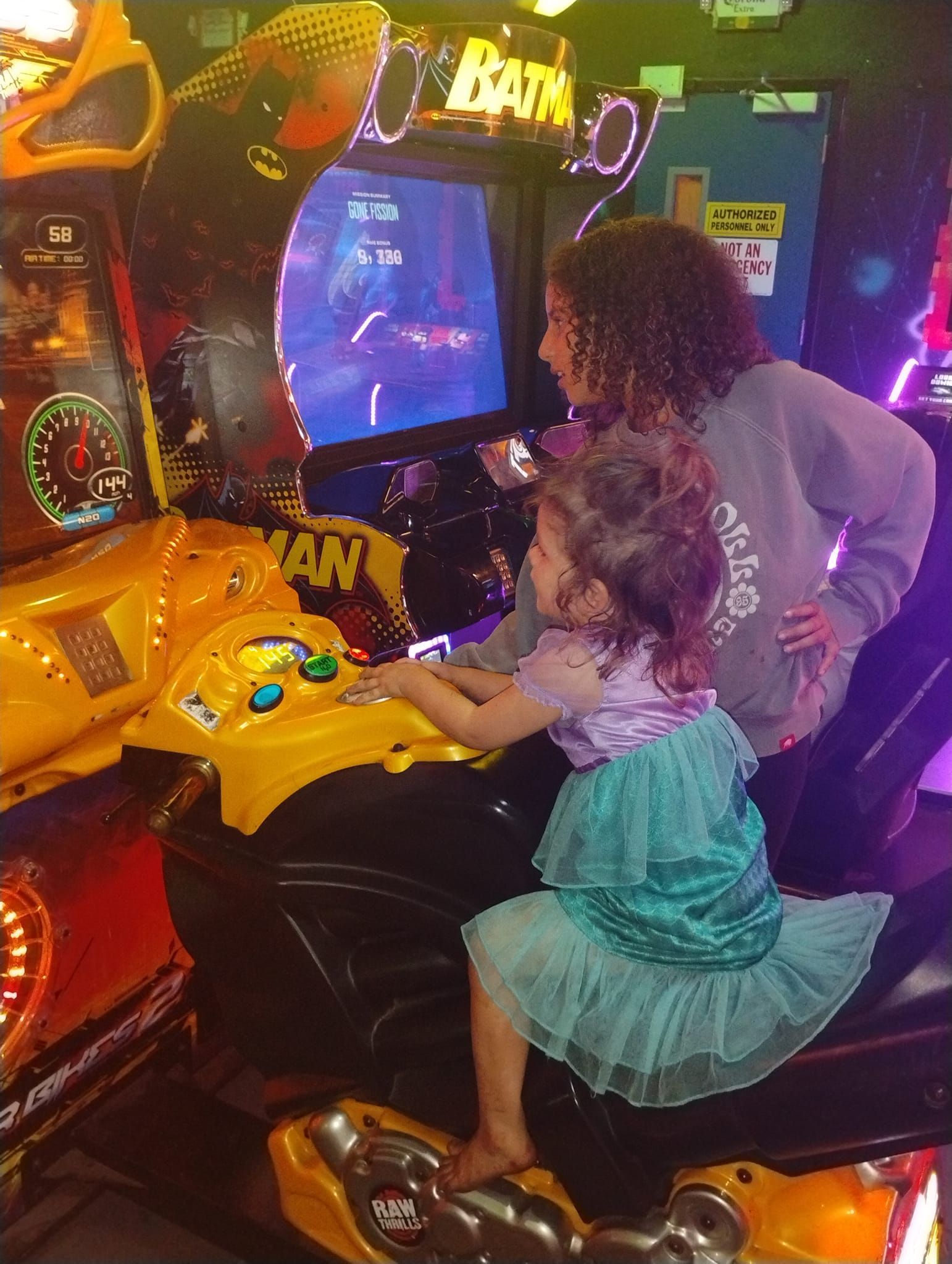 A woman and a little girl are playing an arcade game.