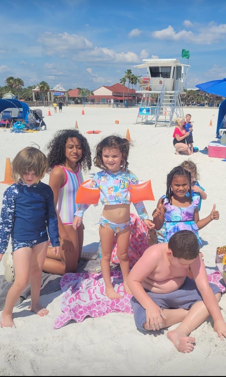 A group of children are posing for a picture on the beach.