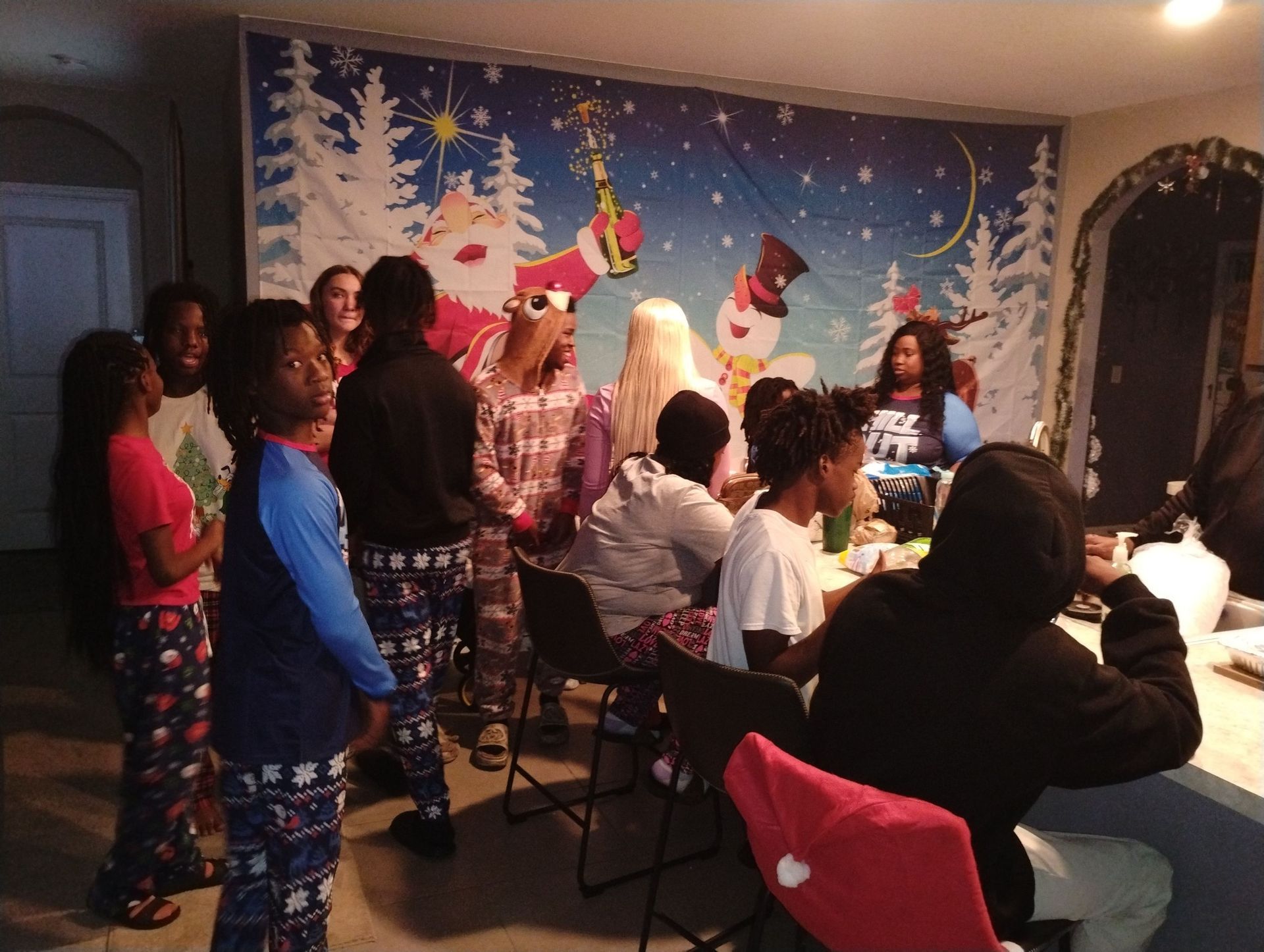 A group of people are standing around a table in front of a christmas poster.