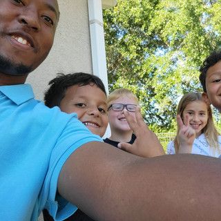 A man is taking a selfie with a group of children.