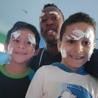 A man and two young boys are posing for a picture with tissues on their faces.