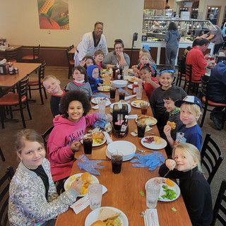 A group of children are sitting at tables in a restaurant eating food.