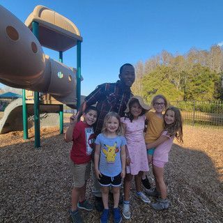 A group of children are posing for a picture in front of a playground.
