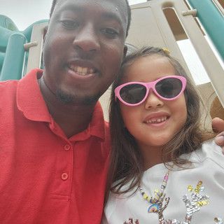 A man and a little girl wearing pink sunglasses are posing for a picture.