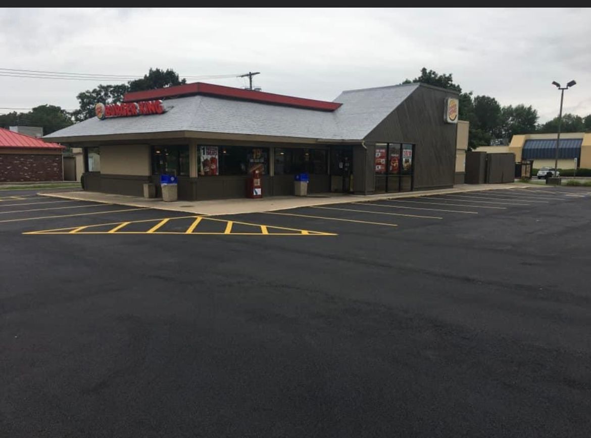 Finished commercial paving job by Universal Paving & Concrete in Rochester, NY, showcasing a sleek, professional surface for a retail business parking lot.