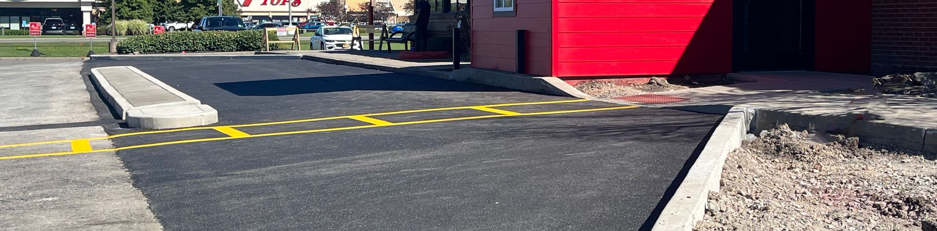 Close-up of a freshly paved commercial parking lot by Universal Paving & Concrete in Rochester, NY, showing a smooth, professional-grade asphalt finish