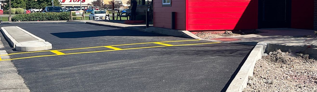 Newly paved commercial parking lot by Universal Paving & Concrete in Rochester, NY, featuring a durable and smooth surface for high-traffic areas.