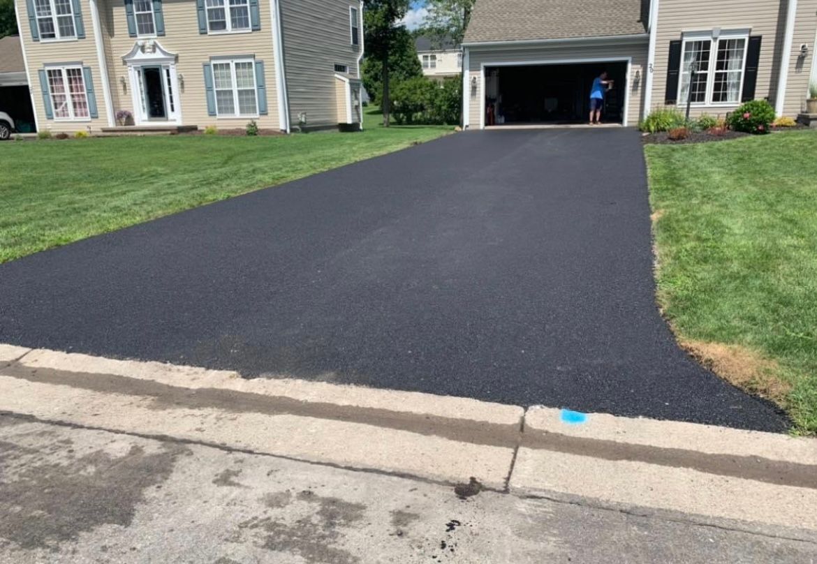 Universal Paving & Concrete team completing an asphalt driveway installation in Rochester, NY, ensuring precise alignment and long-lasting durability.