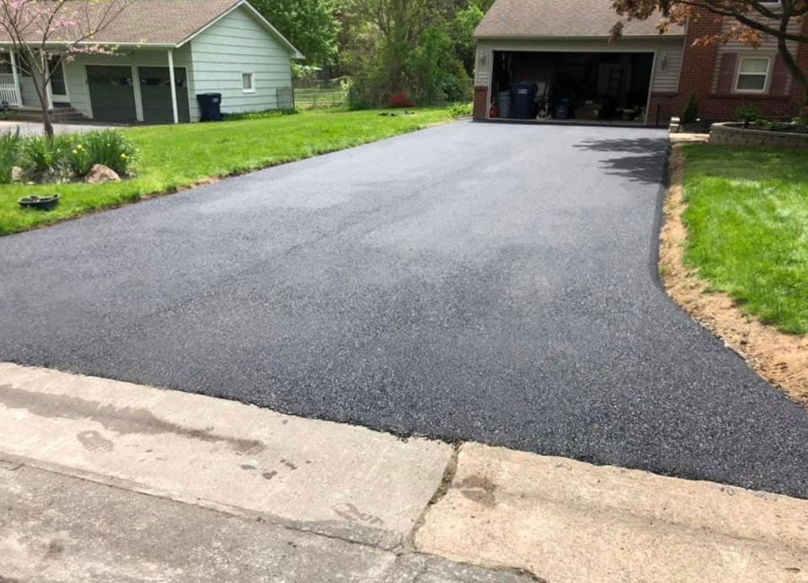 Universal Paving & Concrete laying a new asphalt driveway in Rochester, NY, with attention to detail to ensure evenness and proper slope for drainage