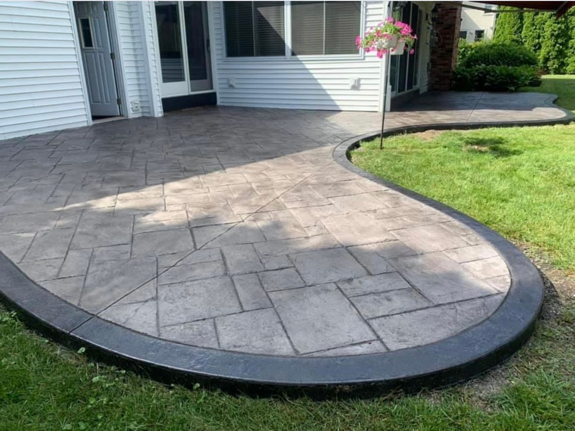 Expertly crafted stamped concrete patio with a natural stone look, installed by Universal Paving & Concrete in Rochester, NY for a stylish outdoor retreat.