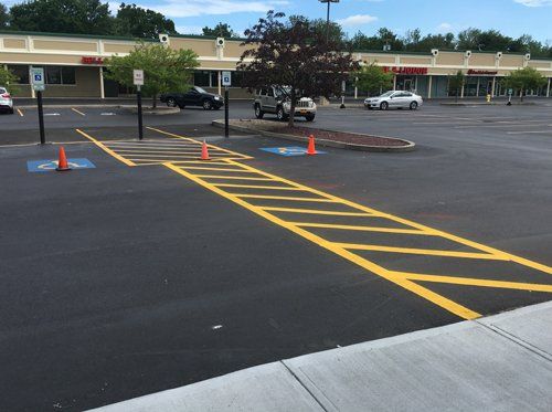 Universal Paving & Concrete completing an ADA paving installation for a commercial property in Rochester, NY, with properly designed ramps and accessible walkways.