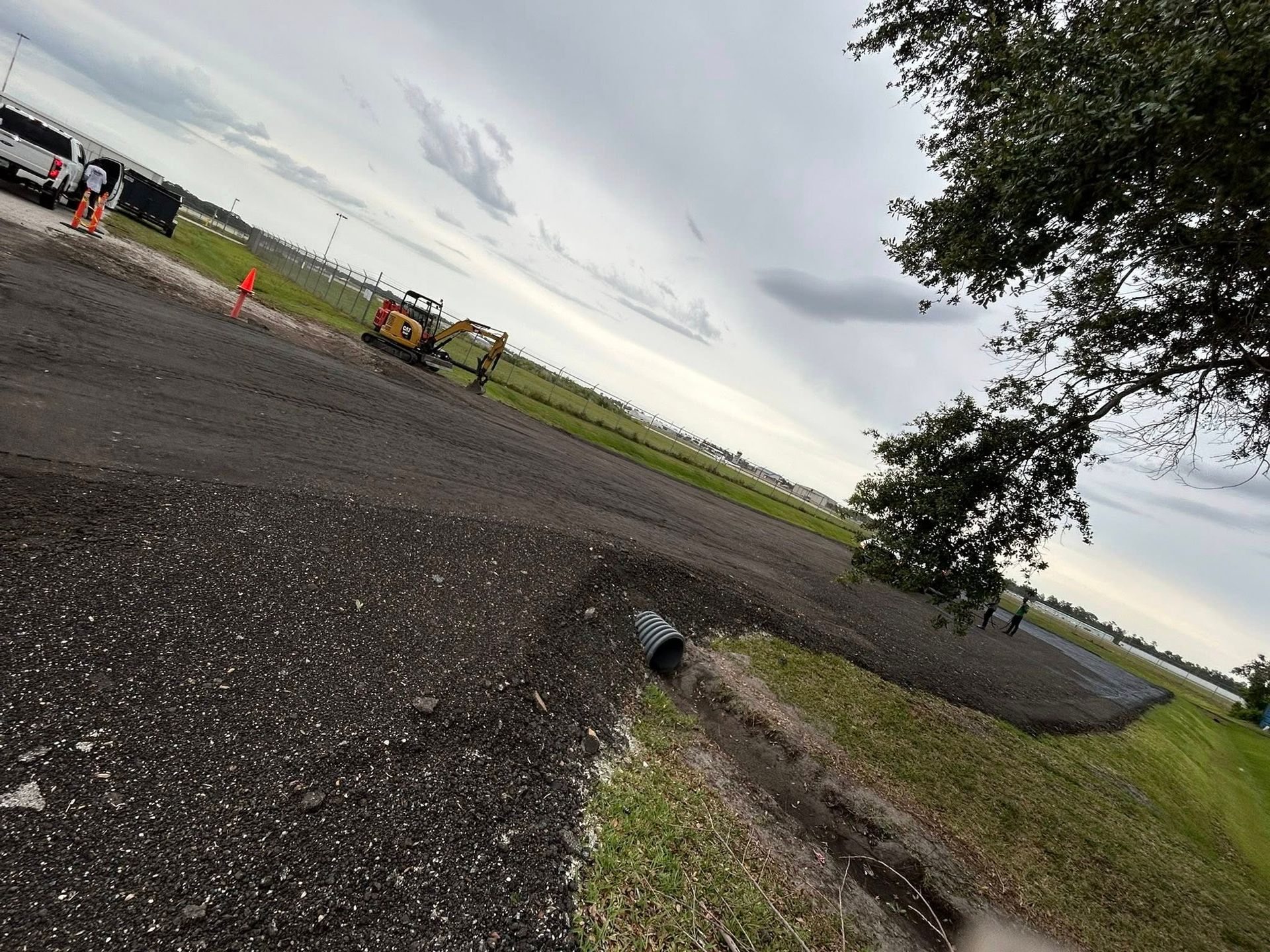 A tractor is driving down a road next to a field.