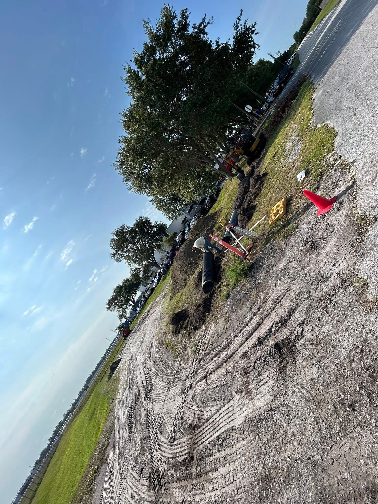 A group of people are standing on the side of a dirt road.