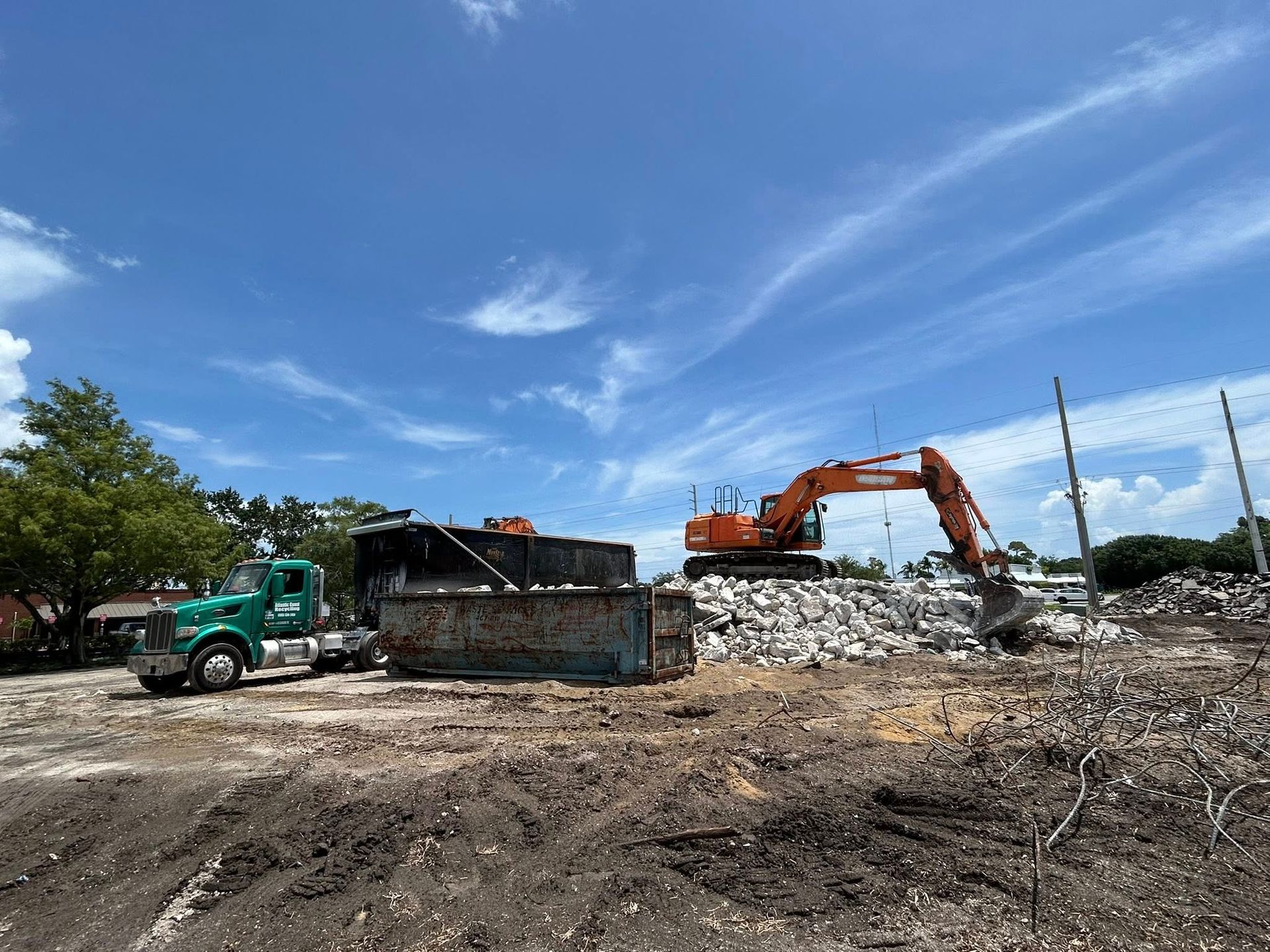 A dump truck is driving down a dirt road next to a large excavator.