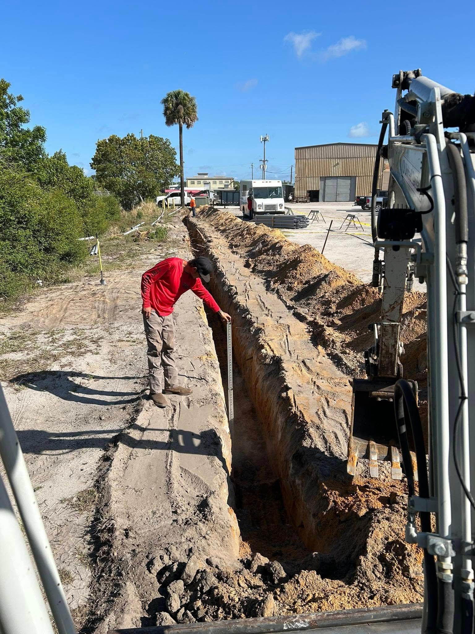 A man in a red shirt is digging a hole in the ground.