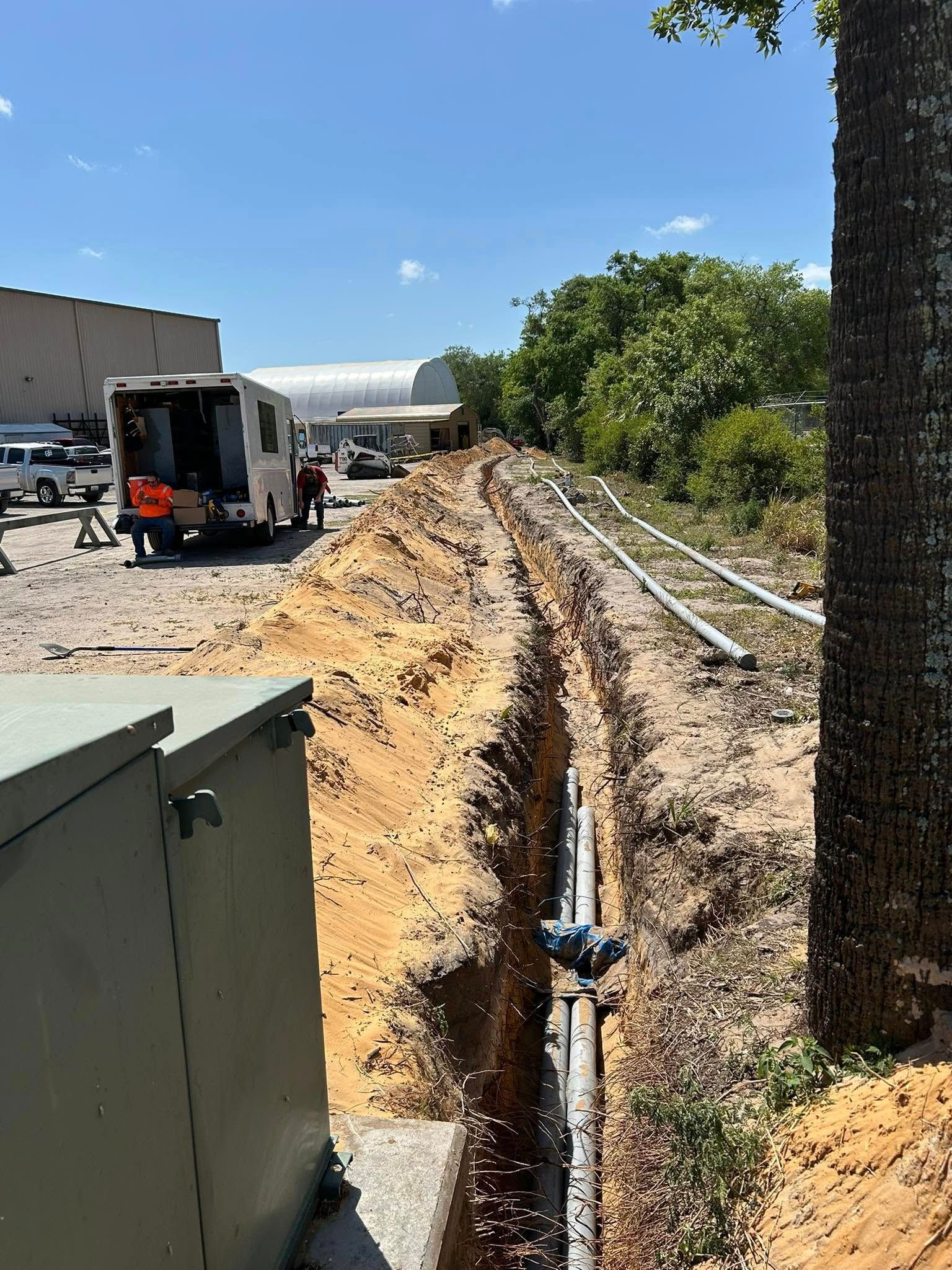 A truck is driving down a dirt road next to a tree.