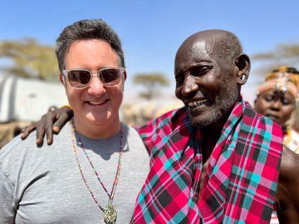 Two men are posing for a picture together and one of them is wearing sunglasses.